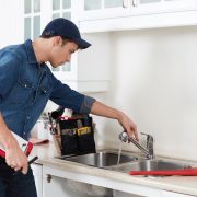 Professional plumber doing reparation in kitchen home.